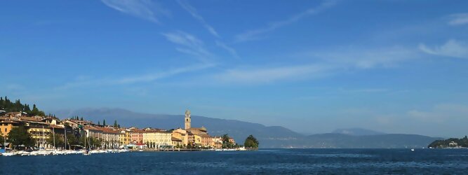 FX Mayr Kur beliebte Urlaubsziele am Gardasee -  Mit einer Fläche von 370 km² ist der Gardasee der größte See Italiens. Es liegt am Fuße der Alpen und erstreckt sich über drei Staaten: Lombardei, Venetien und Trentino. Die maximale Tiefe des Sees beträgt 346 m, er hat eine längliche Form und sein nördliches Ende ist sehr schmal. Dort ist der See von den Bergen der Gruppo di Baldo umgeben. Du trittst aus deinem gemütlichen Hotelzimmer und es begrüßt dich die warme italienische Sonne. Du blickst auf den atemberaubenden Gardasee, der in zahlreichen Blautönen schimmert - von tiefem Dunkelblau bis zu funkelndem Türkis. Majestätische Berge umgeben dich, während die Brise sanft deine Haut streichelt und der Duft von blühenden Zitronenbäumen deine Nase kitzelt. Du schlenderst die malerischen, engen Gassen entlang, vorbei an farbenfrohen, blumengeschmückten Häusern. Vereinzelt unterbricht das fröhliche Lachen der Einheimischen die friedvolle Stille. Du fühlst dich wie in einem Traum, der nicht enden will. Jeder Schritt führt dich zu neuen Entdeckungen und Abenteuern. Du probierst die köstliche italienische Küche mit ihren frischen Zutaten und verführerischen Aromen. Die Sonne geht langsam unter und taucht den Himmel in ein leuchtendes Orange-rot - ein spektakulärer Anblick.
